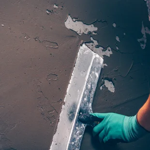 Ausgleich des Untergrunds - Werkzeug für das Planieren der Wände in den Händen des Arbeitnehmers, Arbeit mit einem Spatel, Fliesen die Wände vorbereiten - Stock-Fotografie