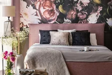 anpassungsfähig - Rosa und grauen Bett mit Kissen in gemusterten Schlafzimmer Innenraum mit Blumen und Lampe. Echtes Foto - Stock-Fotografie